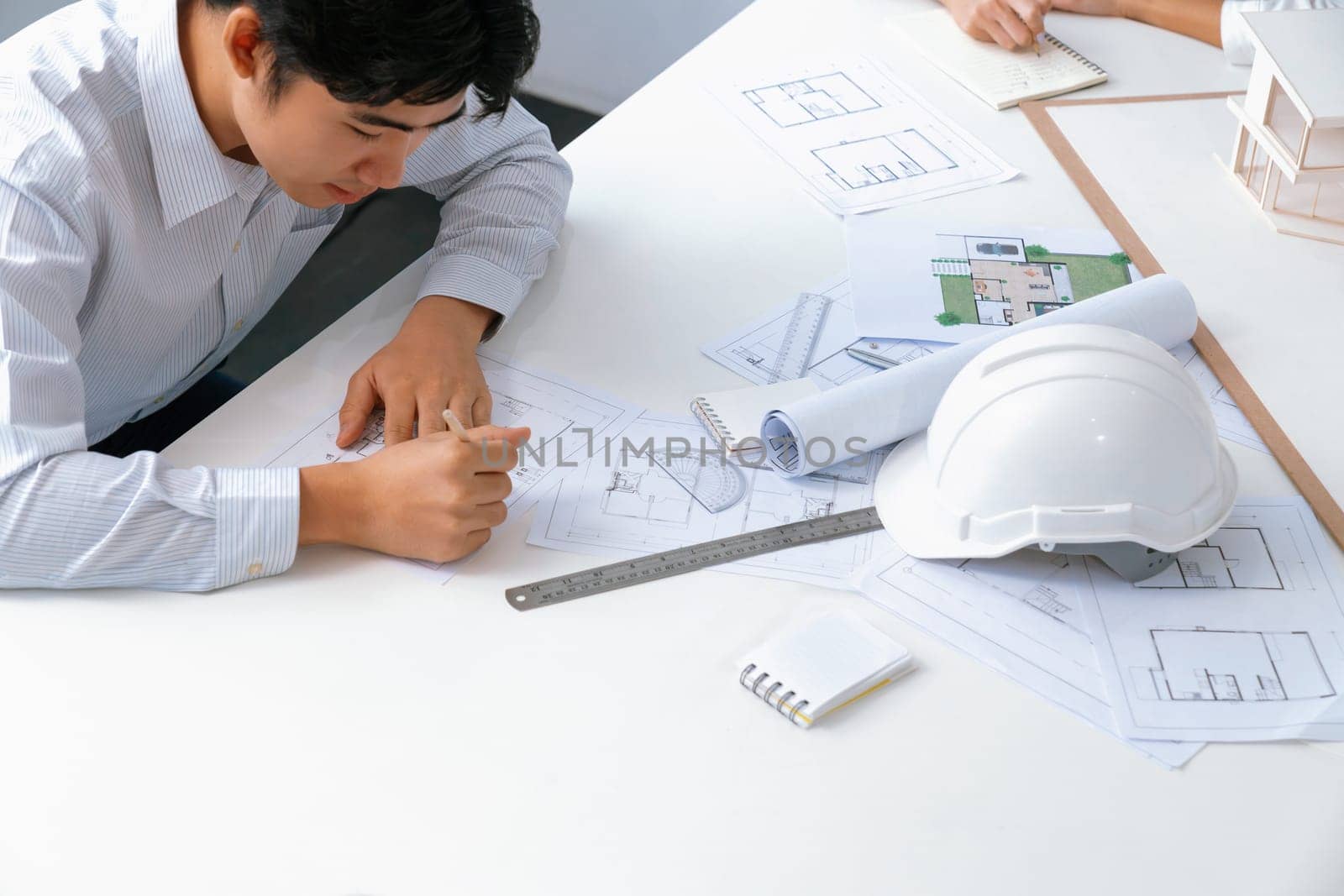 Professional engineer measures house model while skilled interior designer taking a note. Work together, collaboration, cooperative. Creative design and team working concept. Top view. Immaculate.