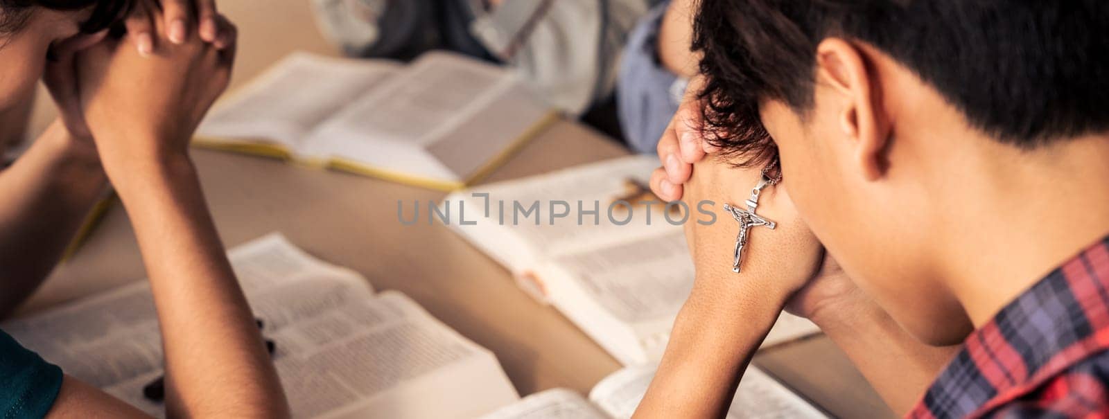 Group of christian pray to god while holding iron cross on holy bible book at church. Concept of hope, religion, faith, christianity and god blessing. Warm background Closeup. Burgeoning.