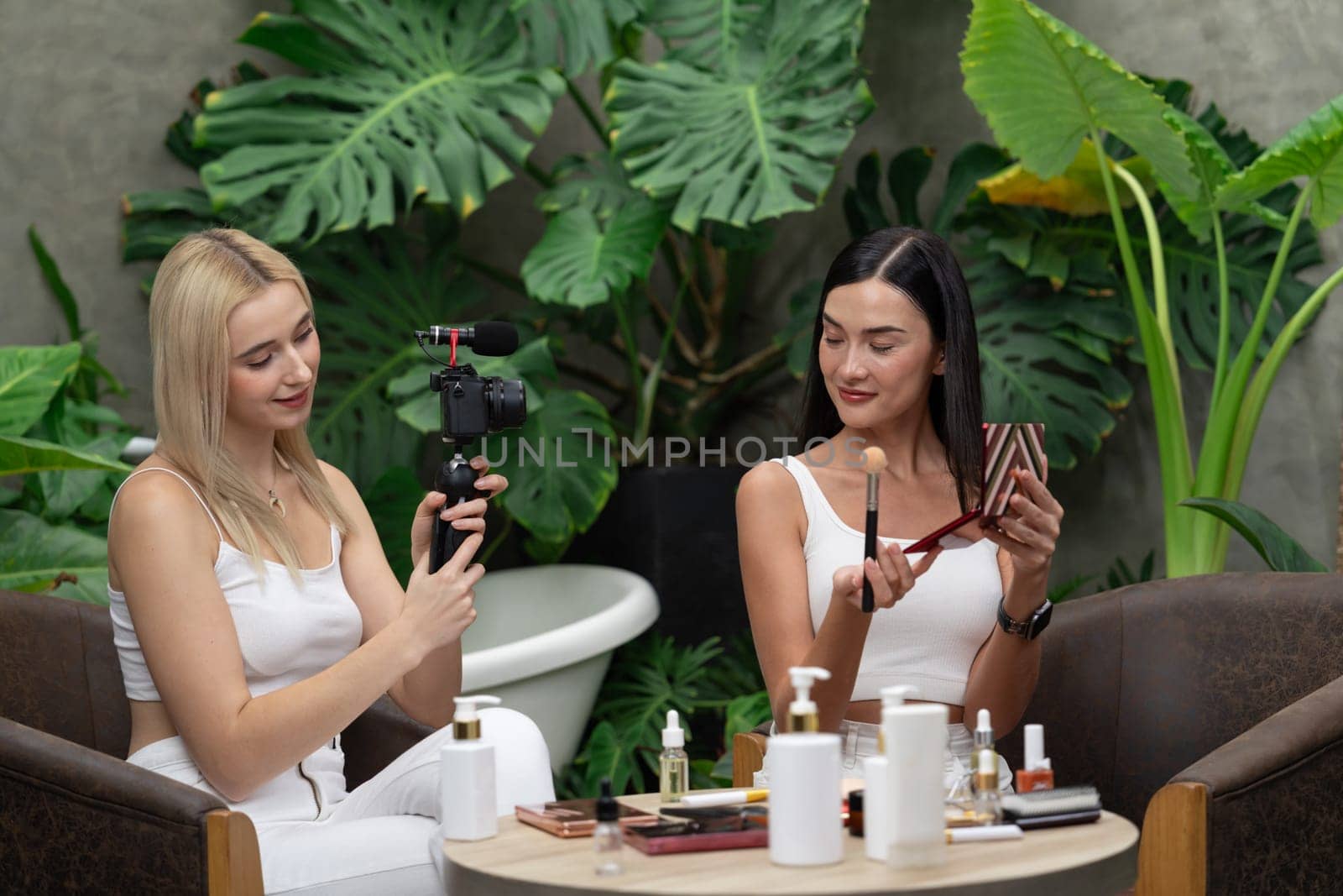 Two beautiful content creator making natural beauty and cosmetic tutorial on green plant garden video. Beauty blogger showing how to beauty care to social medial audience using selfie stick . Blithe