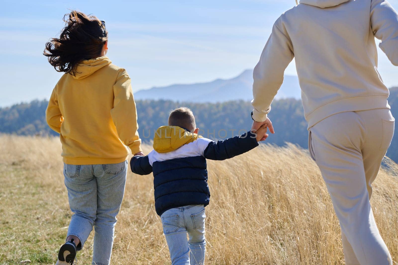 A modern family, along with their son, revels in the joy of a muddy day in nature, running and playing together, encapsulating the beauty of a healthy and active lifestyle.