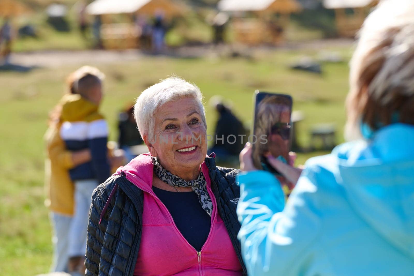 An elderly pair of women captures a timeless moment on their smartphones, blending technology with the serene beauty that surrounds them.