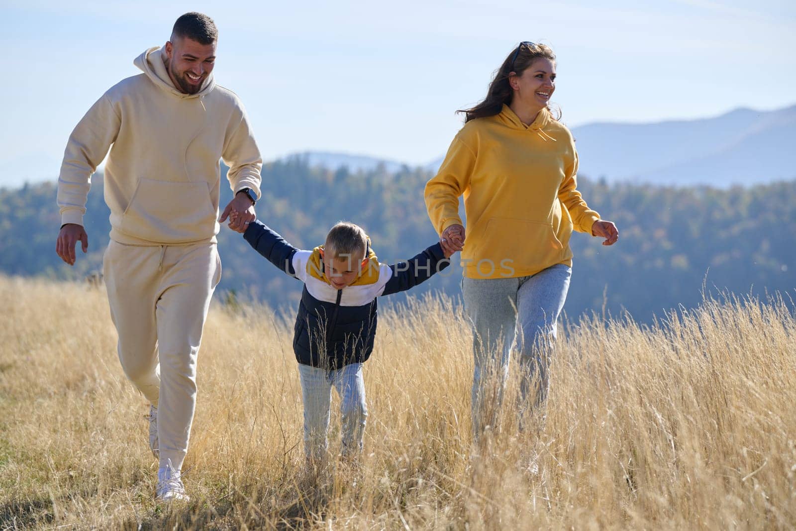 A modern family, along with their son, revels in the joy of a muddy day in nature, running and playing together, encapsulating the beauty of a healthy and active lifestyle.