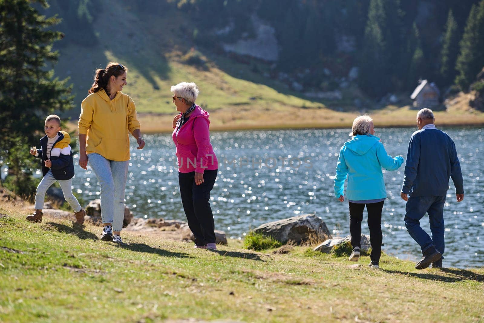 A family shares delightful moments with their friends amid the stunning landscapes of mountains, lakes, and winding paths, promoting a healthy lifestyle and the joy of familial bonds in the embrace of nature's beauty.