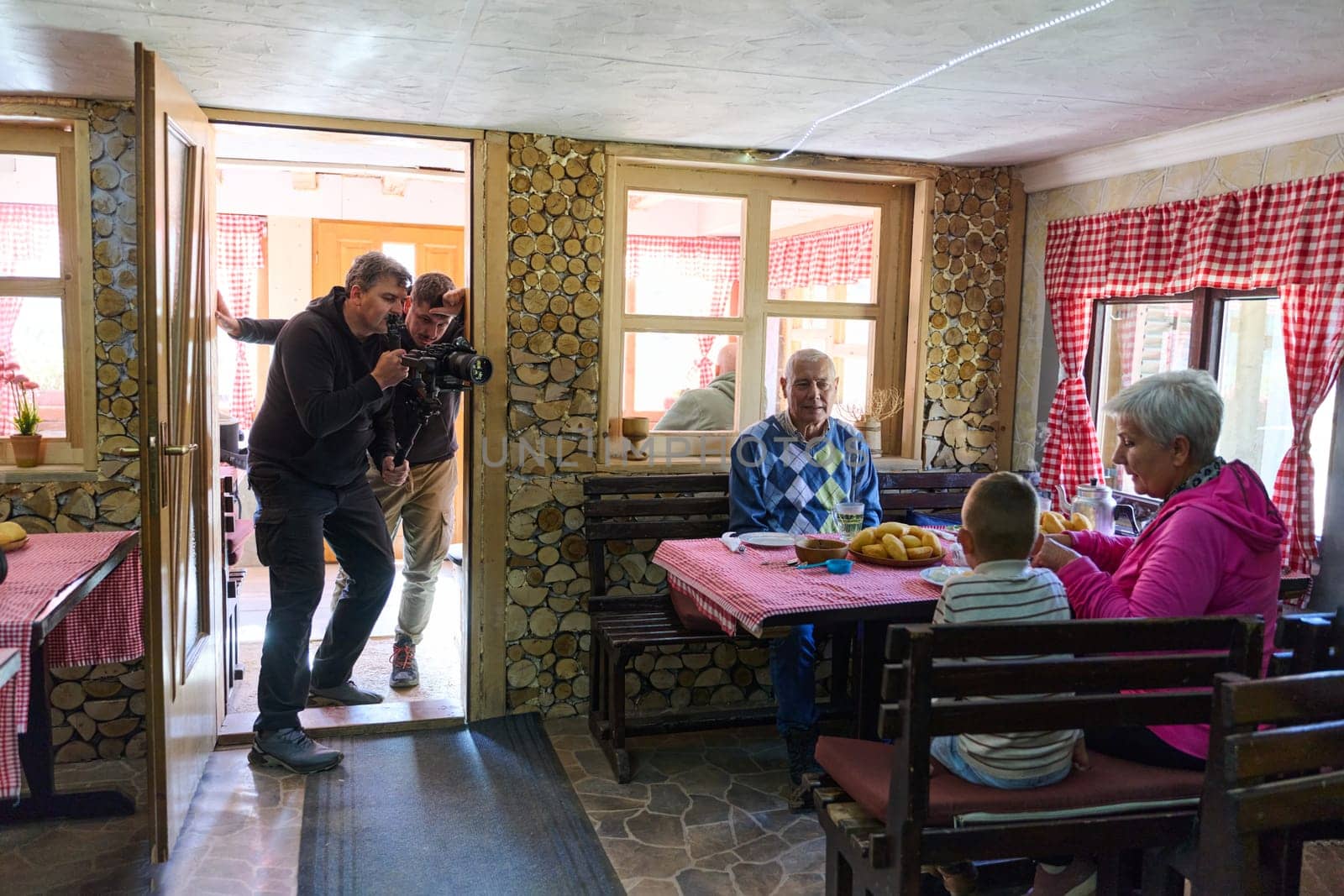 Videographers expertly capture the cinematic beauty of an elderly couple sharing a heartwarming breakfast with their grandchild at a rustic weekend retreat, preserving the cherished memories of generational love and togetherness.