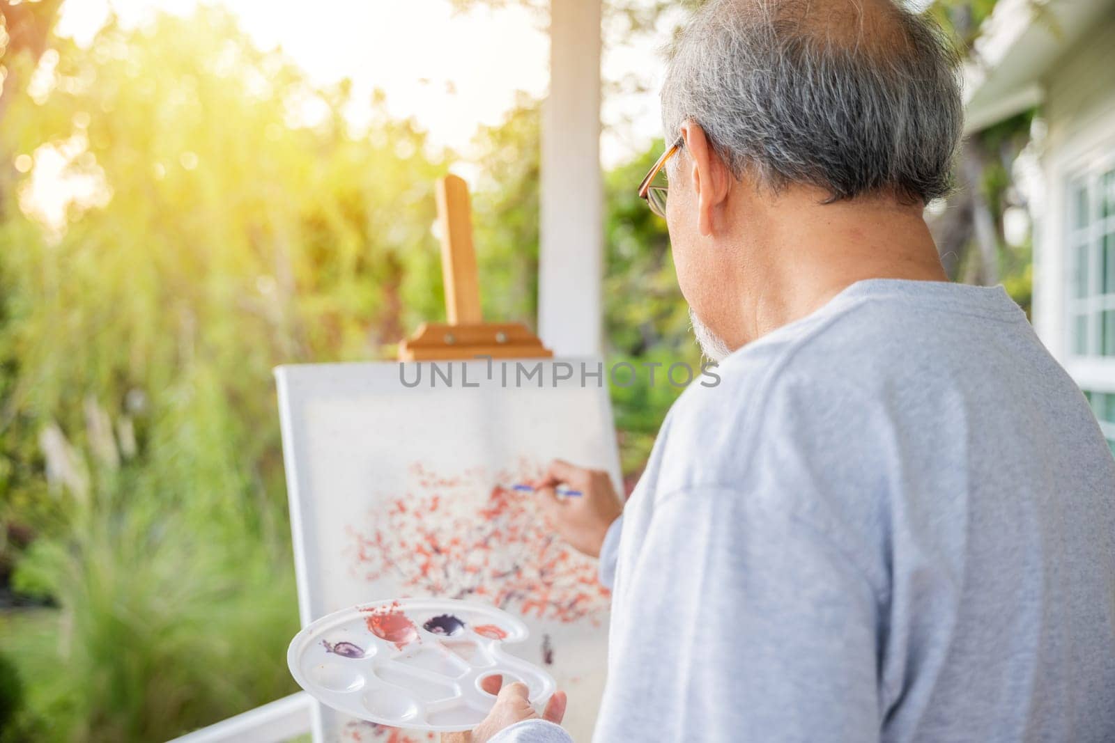 Asian senior old man painting picture using brush and oil color on canvas by Sorapop