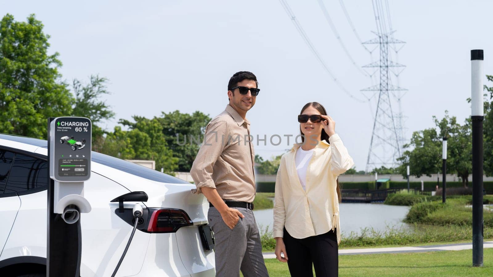 Young couple recharge EV car battery at charging station. Expedient by biancoblue