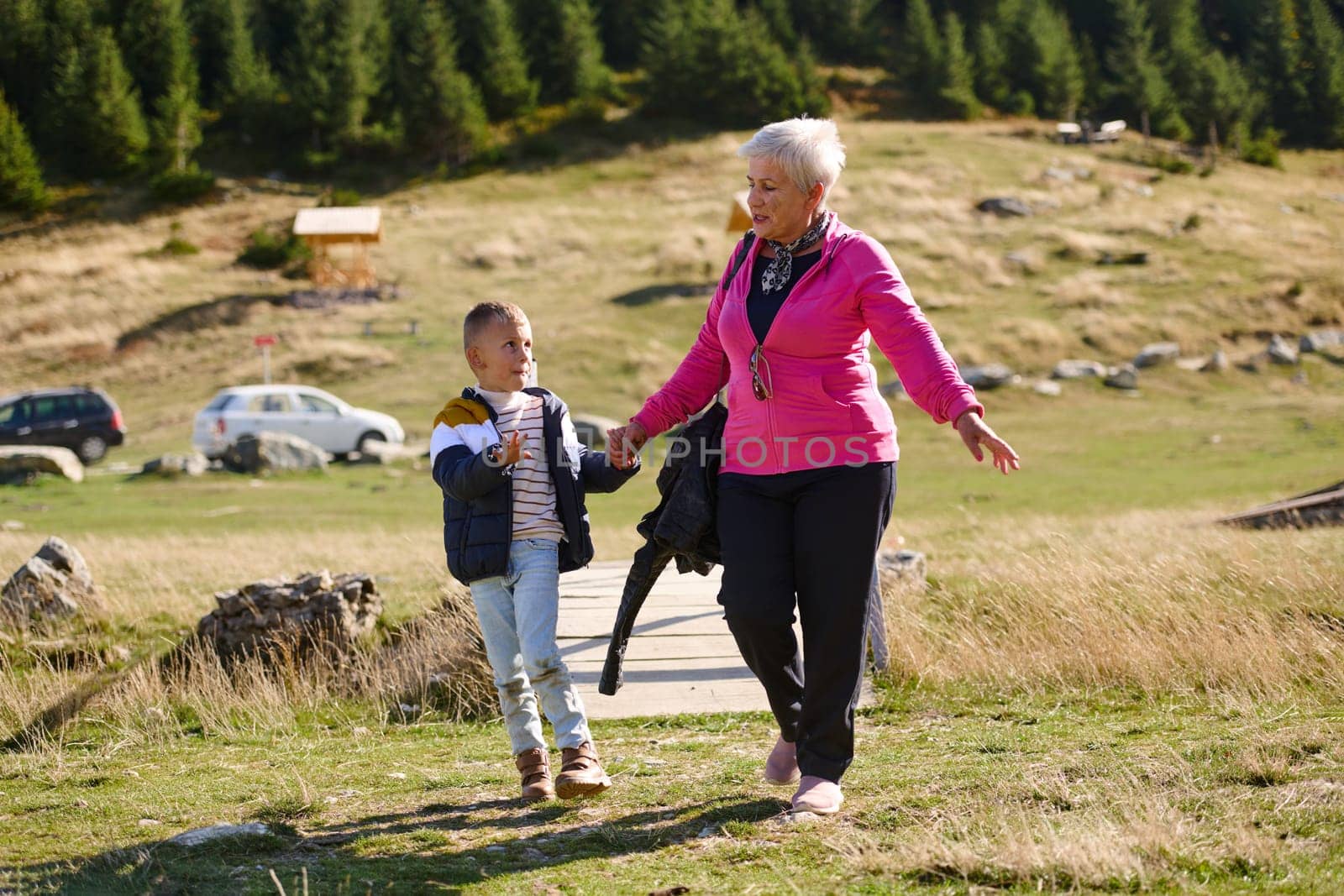 Elderly grandmother and her grandchild share a leisurely stroll through nature, enveloped in the beauty of their surroundings, fostering a bond that transcends generations.