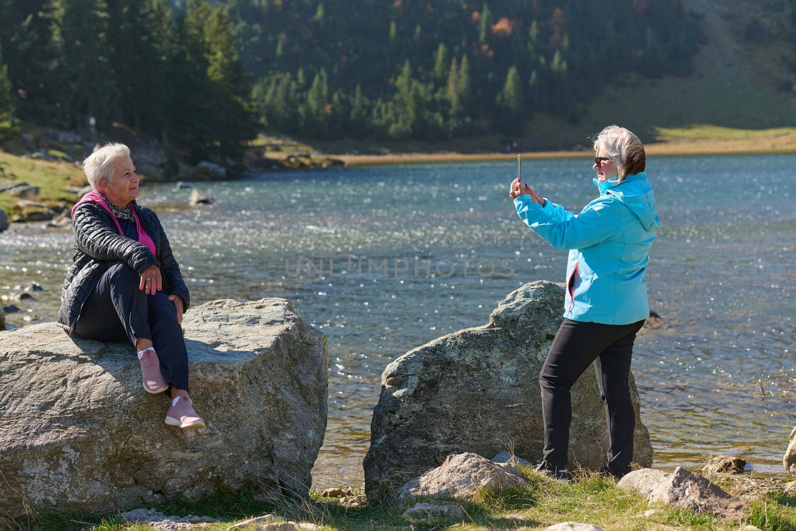 An elderly pair of women captures a timeless moment on their smartphones, blending technology with the serene beauty that surrounds them.