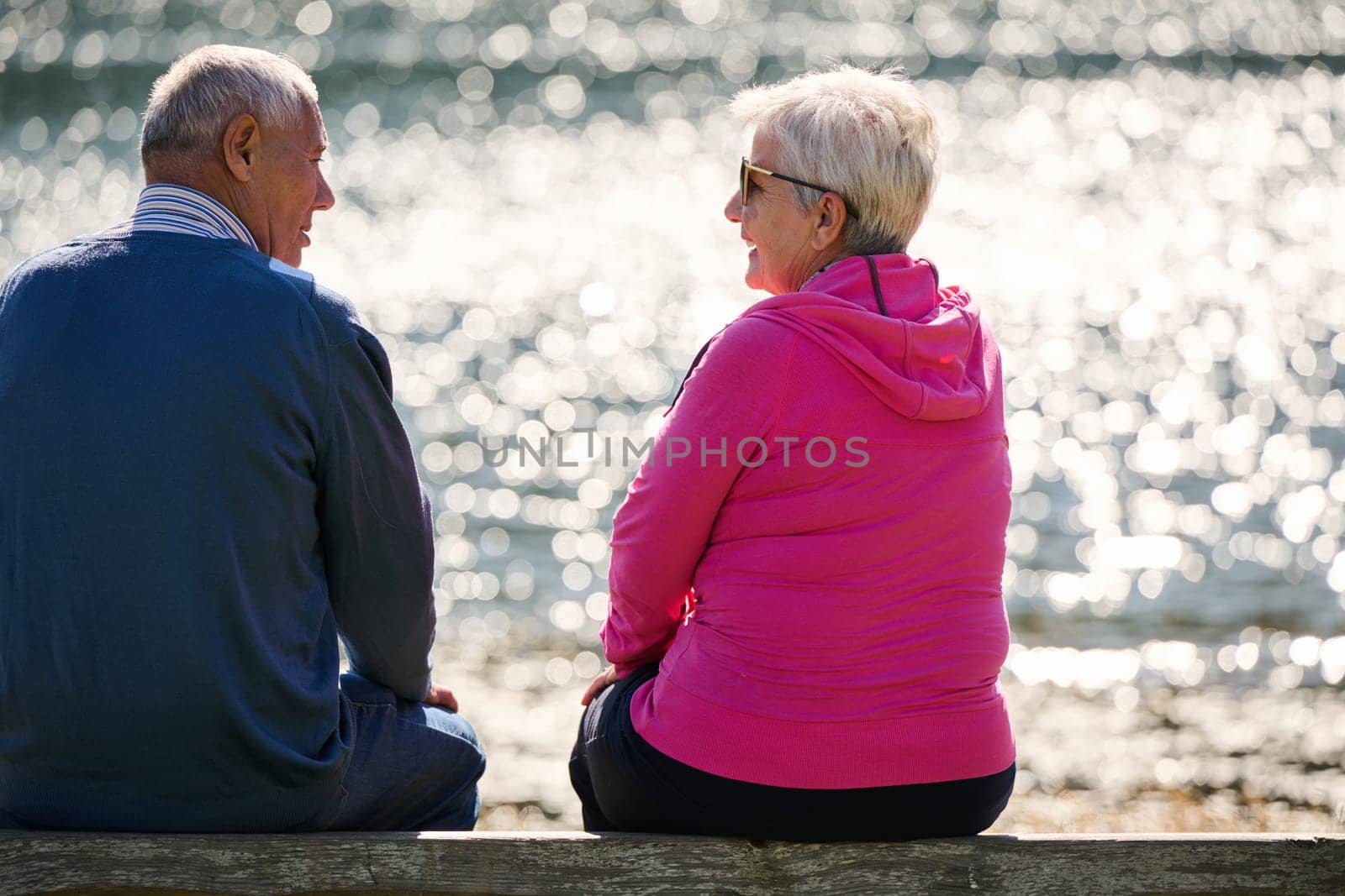 Elderly couple finding solace and joy as they rest on a park bench, engaged in heartfelt conversation, following a rejuvenating strol a testament to the enduring companionship and serene connection that accompanies the golden years.