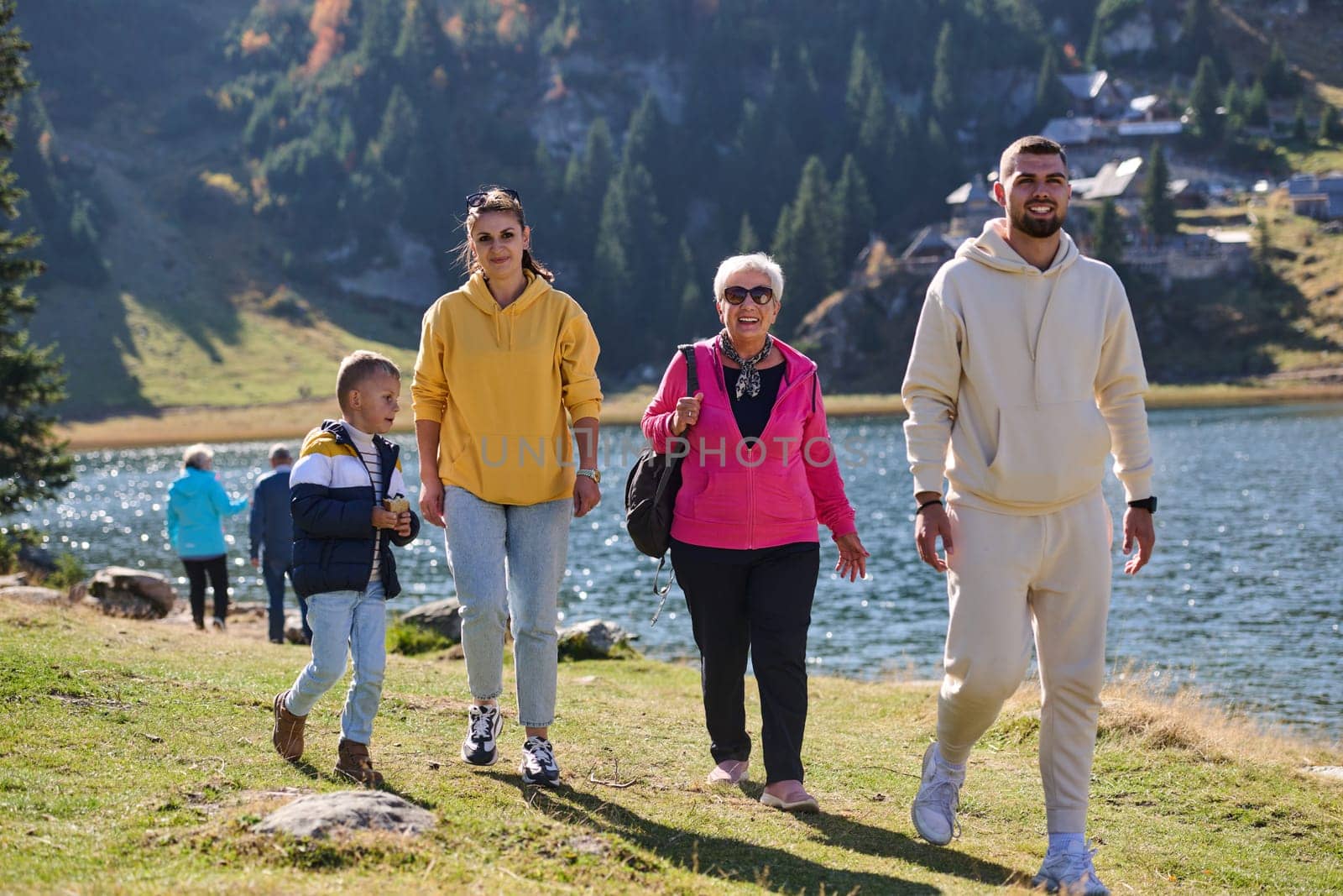 A family shares delightful moments with their friends amid the stunning landscapes of mountains, lakes, and winding paths, promoting a healthy lifestyle and the joy of familial bonds in the embrace of nature's beauty by dotshock