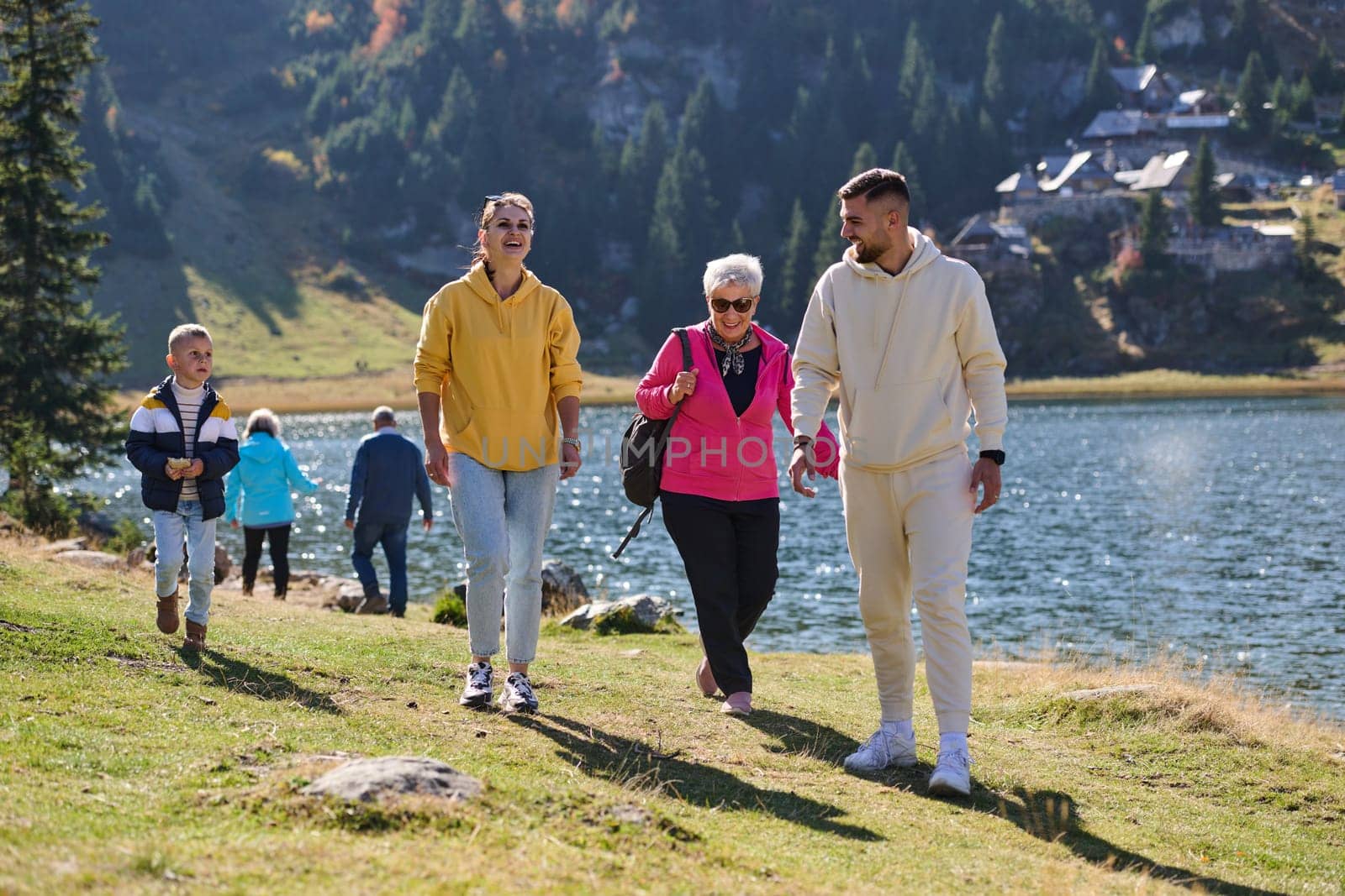 A family shares delightful moments with their friends amid the stunning landscapes of mountains, lakes, and winding paths, promoting a healthy lifestyle and the joy of familial bonds in the embrace of nature's beauty.