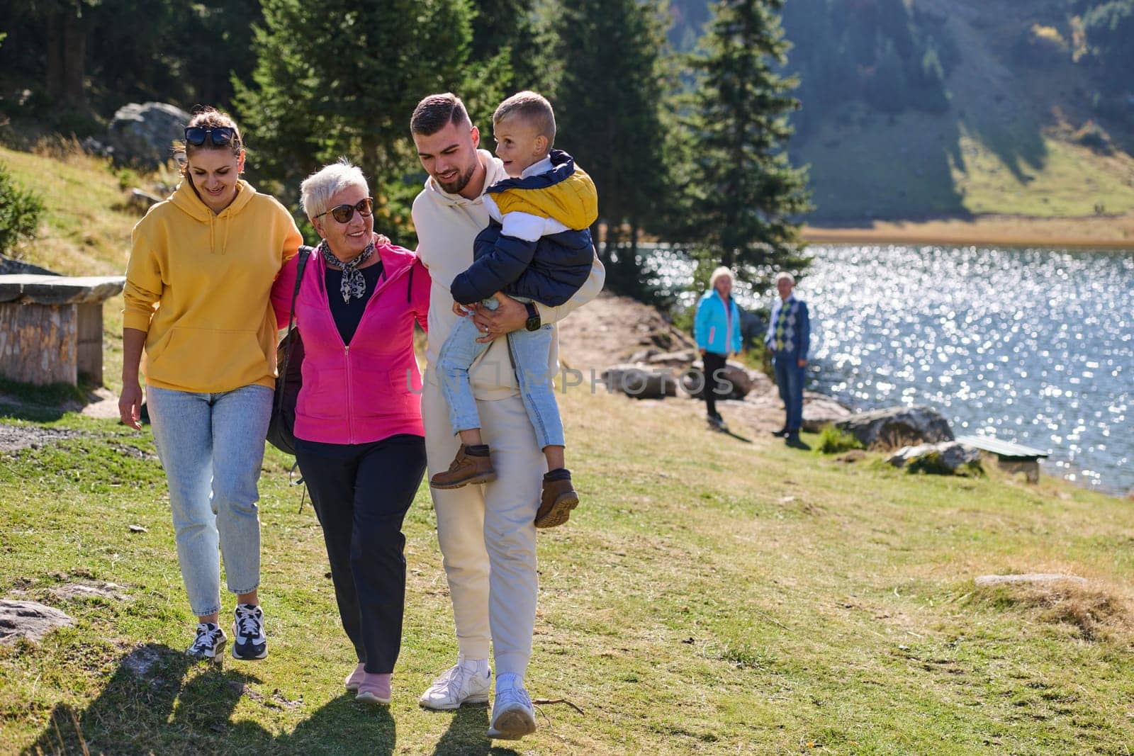 A family shares delightful moments with their friends amid the stunning landscapes of mountains, lakes, and winding paths, promoting a healthy lifestyle and the joy of familial bonds in the embrace of nature's beauty by dotshock