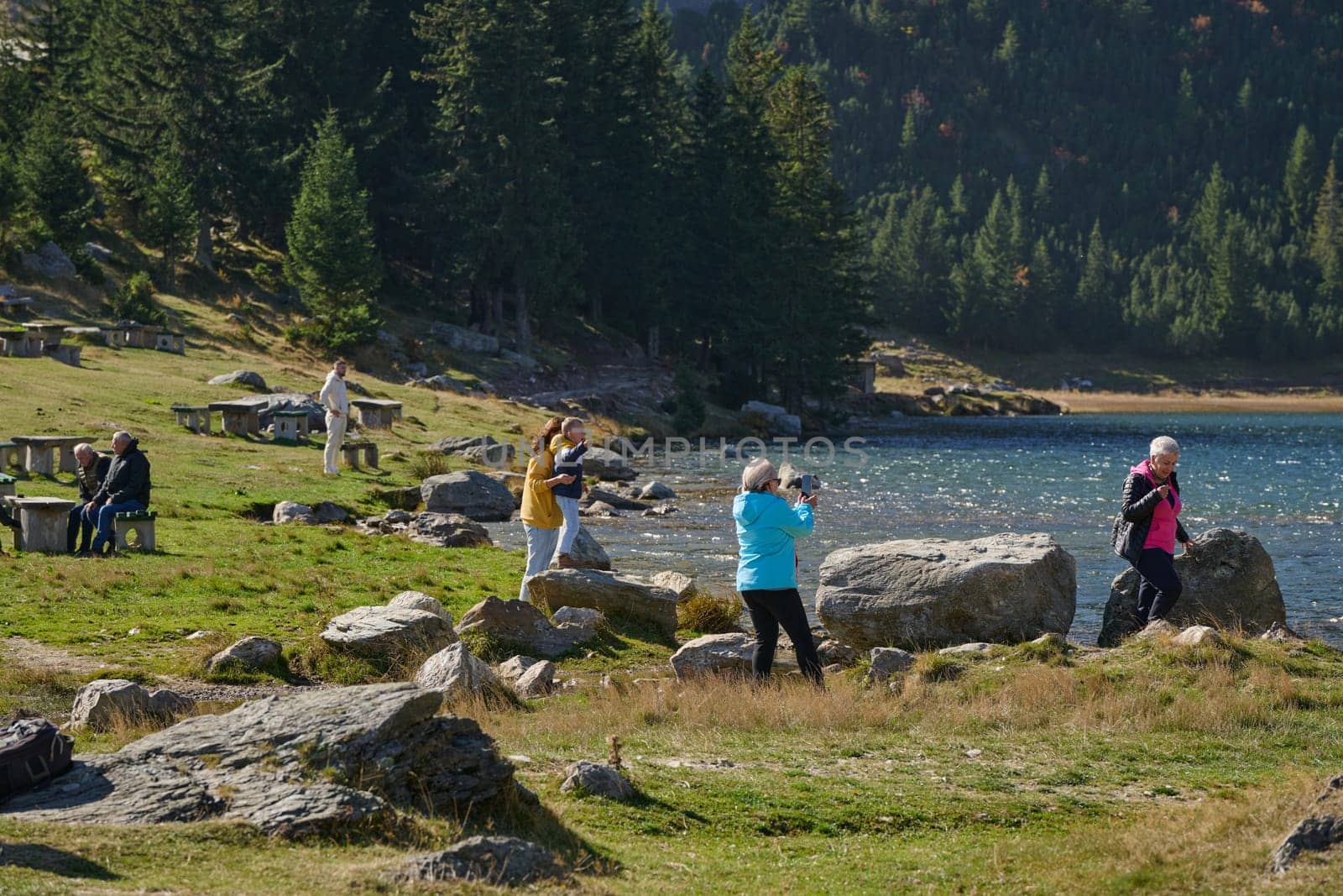 A family shares delightful moments with their friends amid the stunning landscapes of mountains, lakes, and winding paths, promoting a healthy lifestyle and the joy of familial bonds in the embrace of nature's beauty.