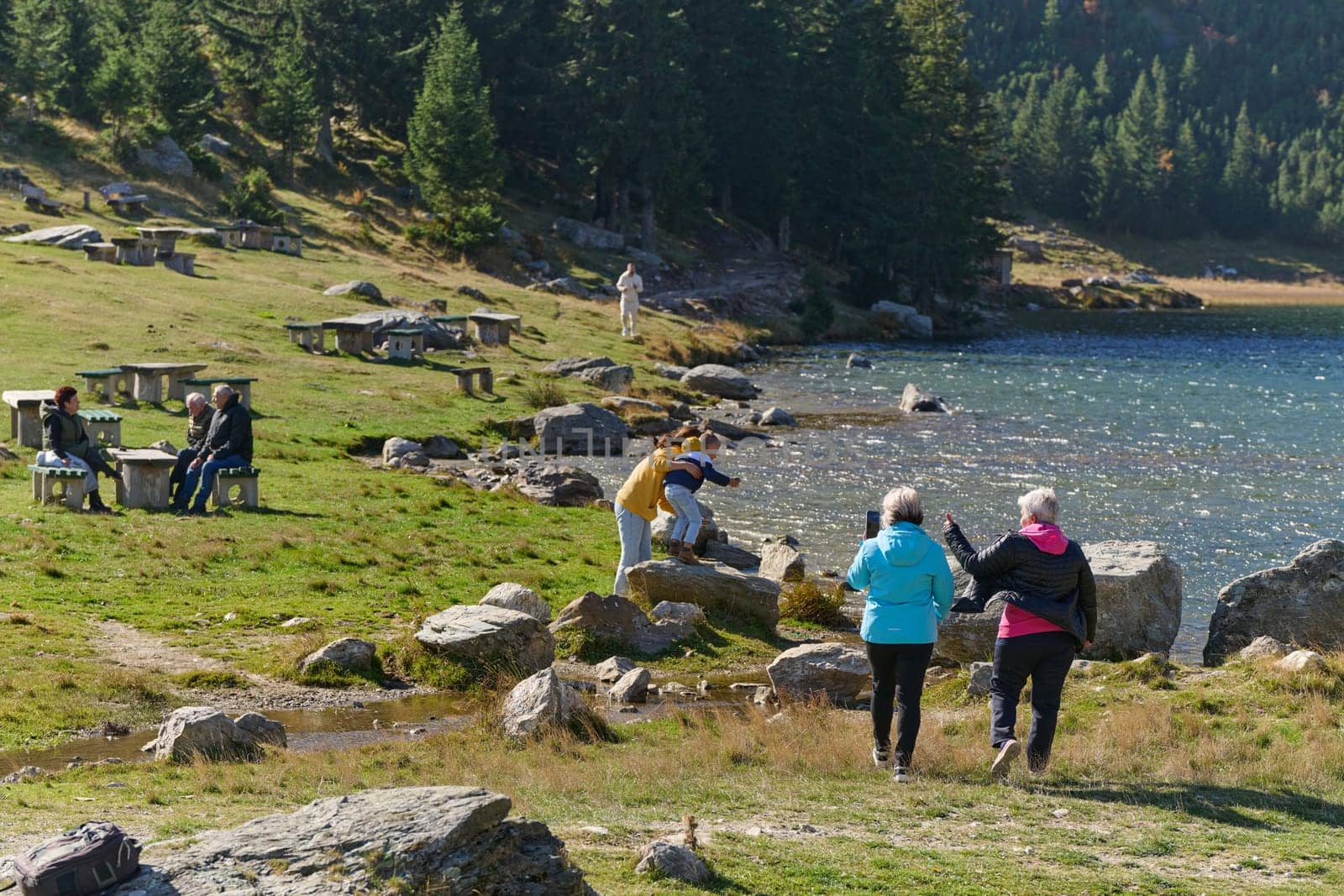 A family shares delightful moments with their friends amid the stunning landscapes of mountains, lakes, and winding paths, promoting a healthy lifestyle and the joy of familial bonds in the embrace of nature's beauty.