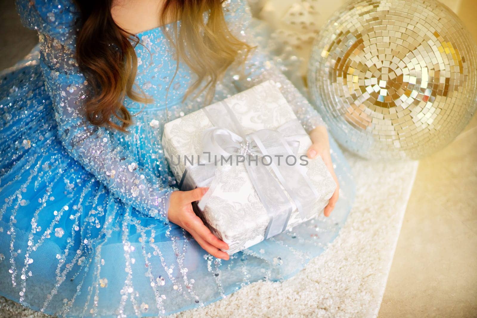 Female hands hold a gift box. Christmas, new year, birthday concept. The girl is dressed in a blue dress and holds out a gift