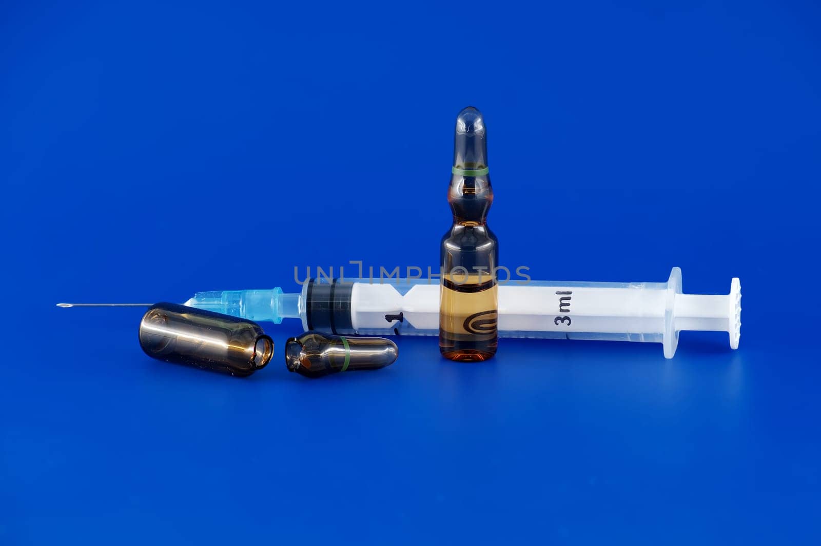 Close-up view of syringe and ampoule over blue by NetPix