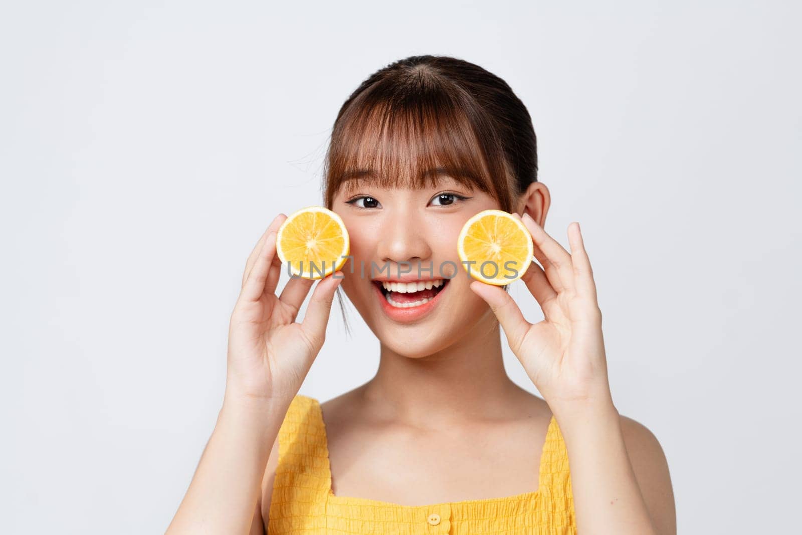 Portrait of beautiful young woman with fresh lemon near face over white background.  by makidotvn