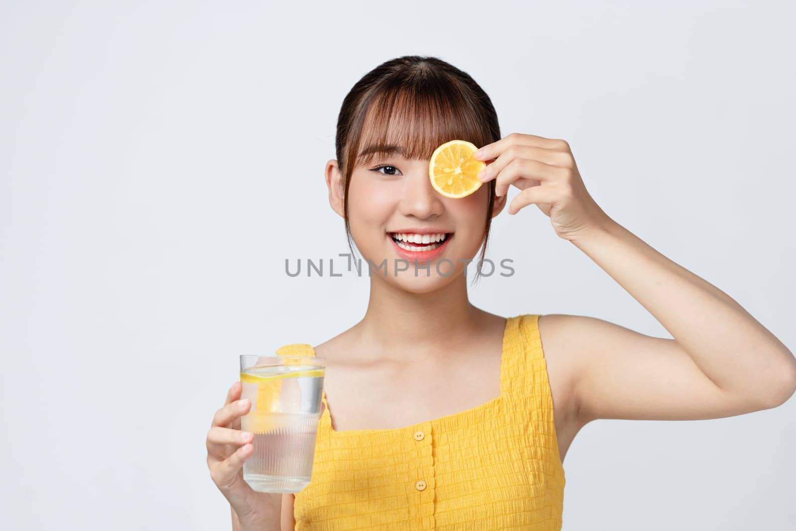 Beautiful young woman with healthy, well-kept skin taking care after health, drinking water with lemons by makidotvn