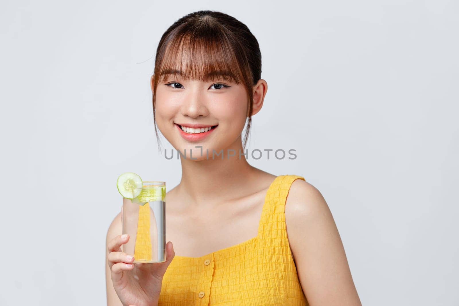 young beautiful woman standing on a white wall, relaxing with a fresh water with lemon by makidotvn