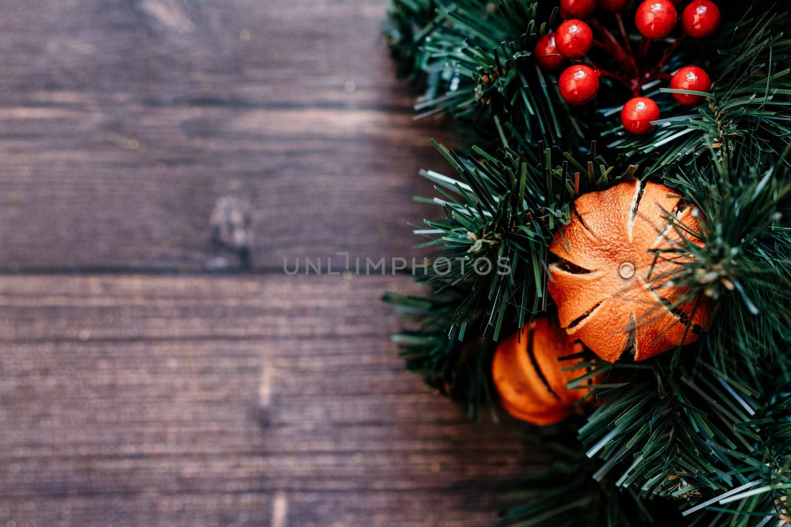 christmas background pine tree with dried tangerines wooden background. The combination of the pine tree, ornaments, and greenery creates a classic and cozy setting