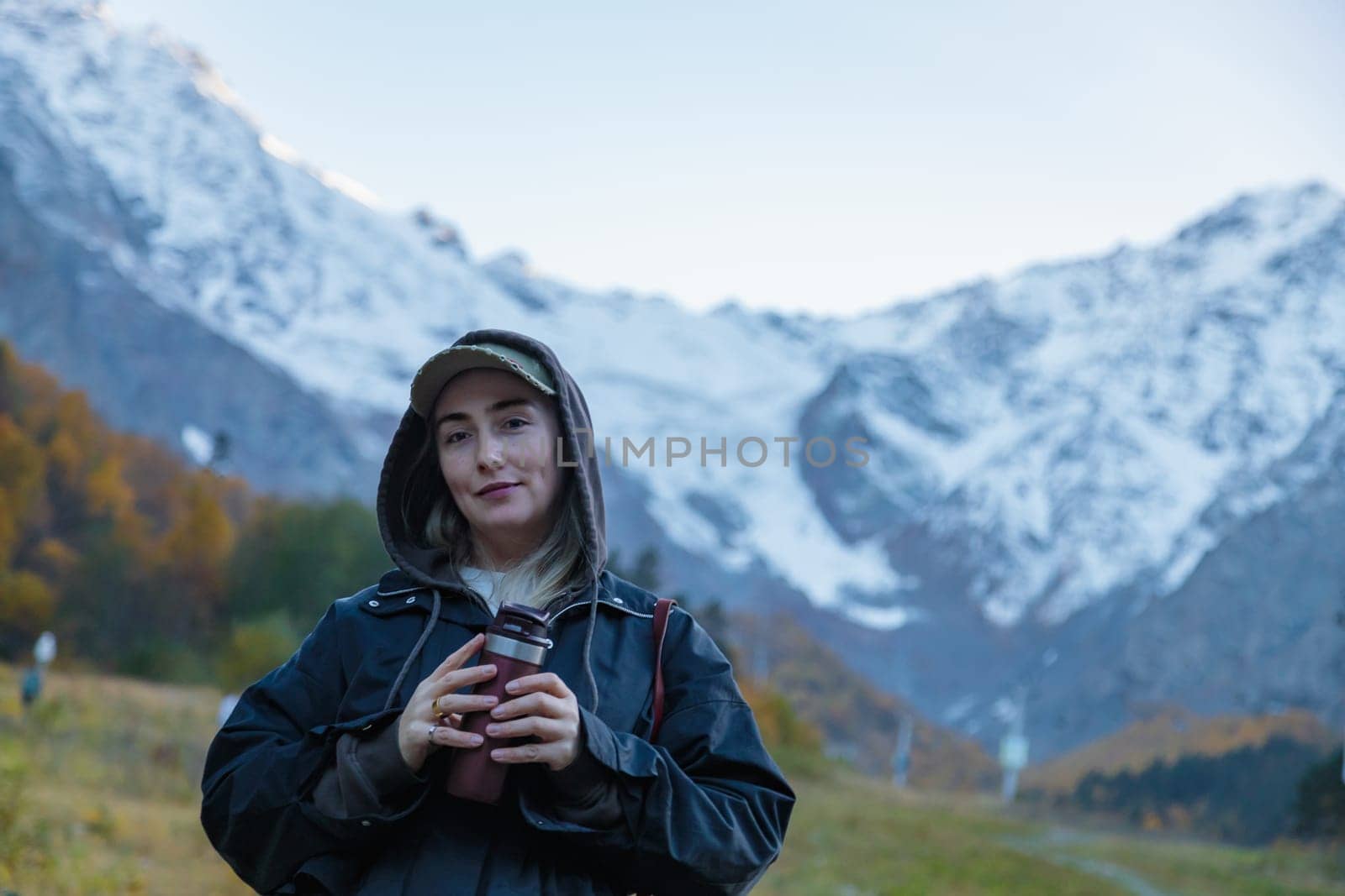 Girl with a thermos on the background of a glacier drinking coffee in the mountains by Yurich32