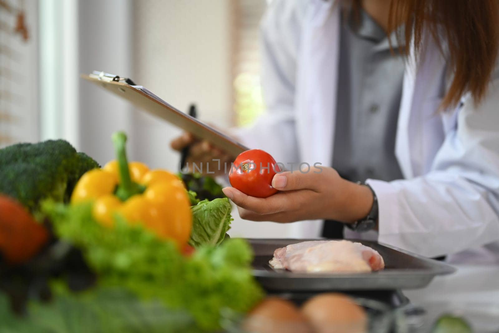 Professional nutritionist in white coat working at desk with vegetables. Healthcare and diet concept.