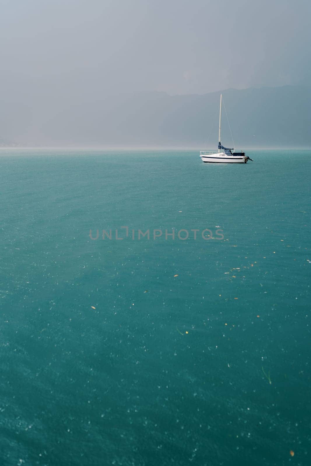Sailing yacht sails on the sea against the backdrop of a storm in the mountains. High quality photo