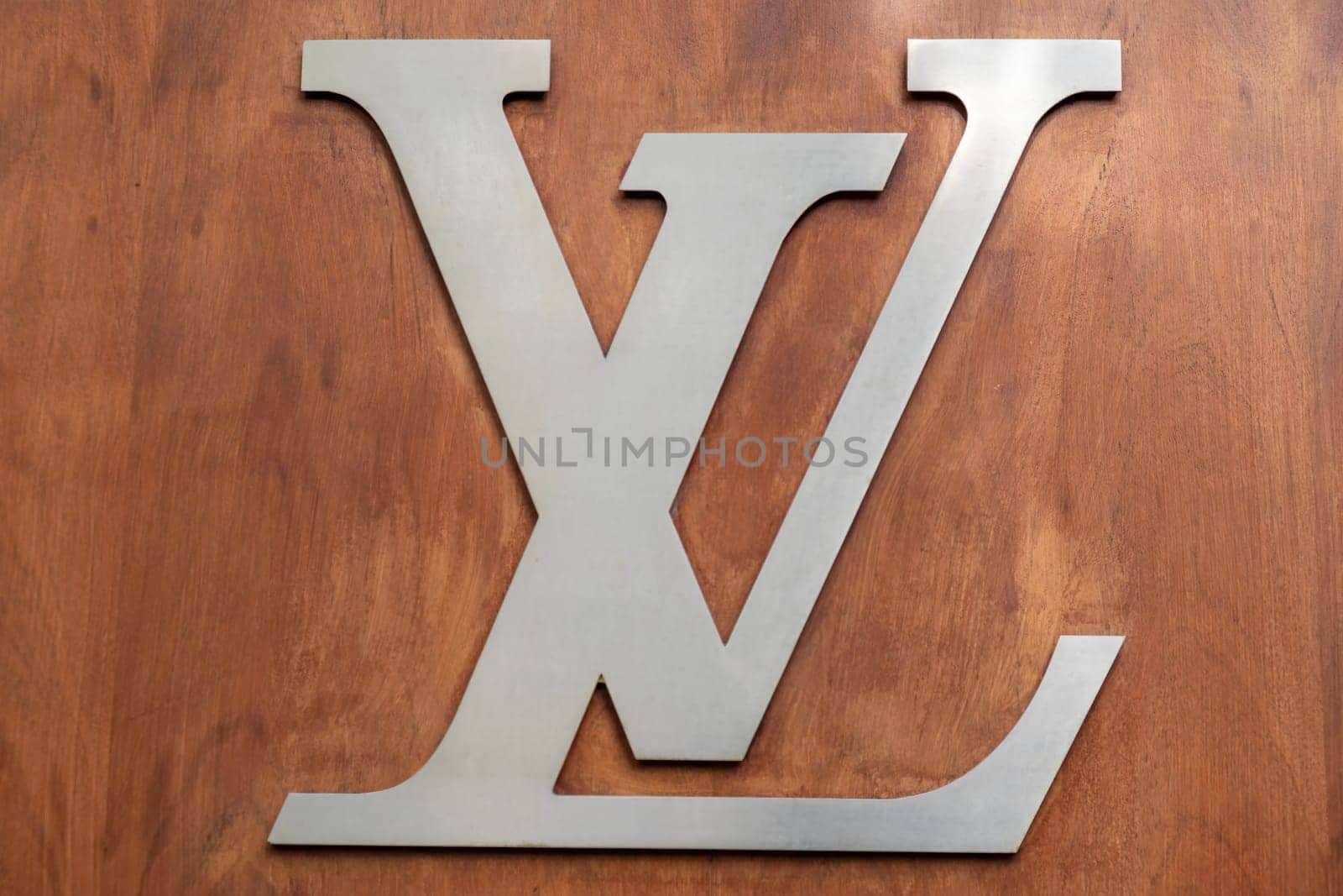 4 May 2023 Paris, France. Close up of Louis Vuitton signature brand logo in brushed chrome on a wood paneled wall. Louis Vuitton has stood for quality, luxury and fashion since 1854. High quality photo