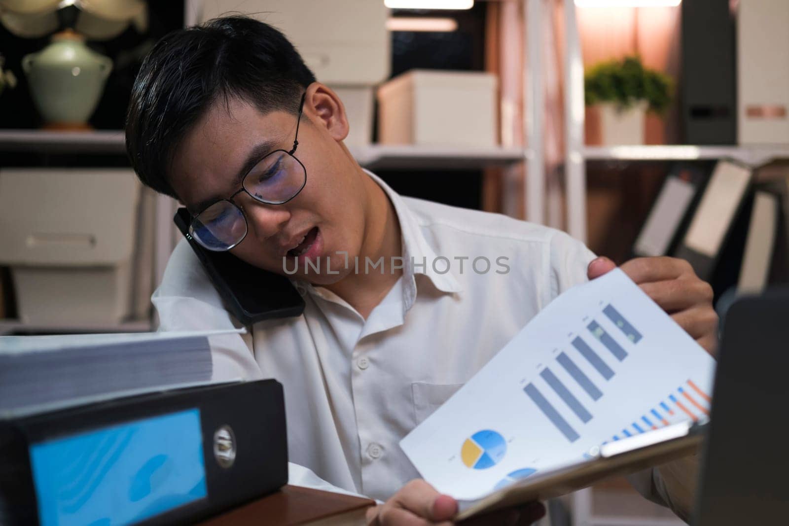 Young Asian businessman working tired office worker sitting at desk using computer and doing overtime project.