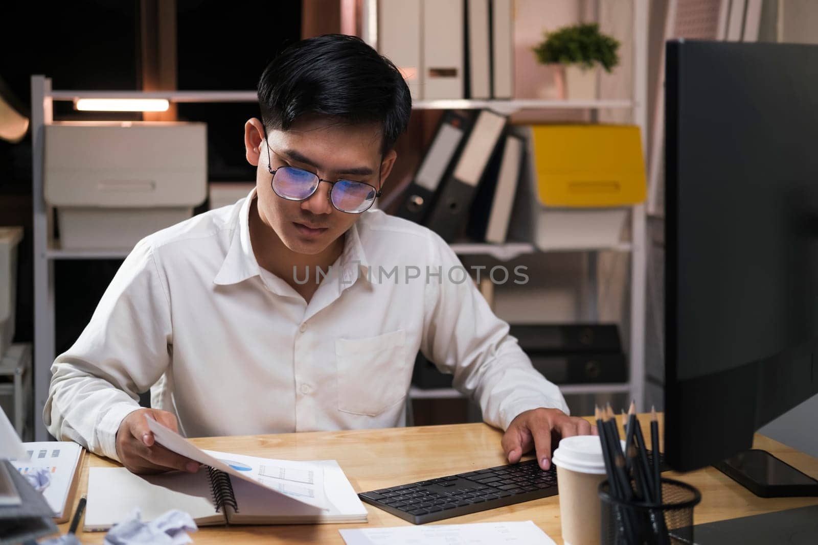 Young Asian businessman working tired office worker sitting at desk using computer and doing overtime project.