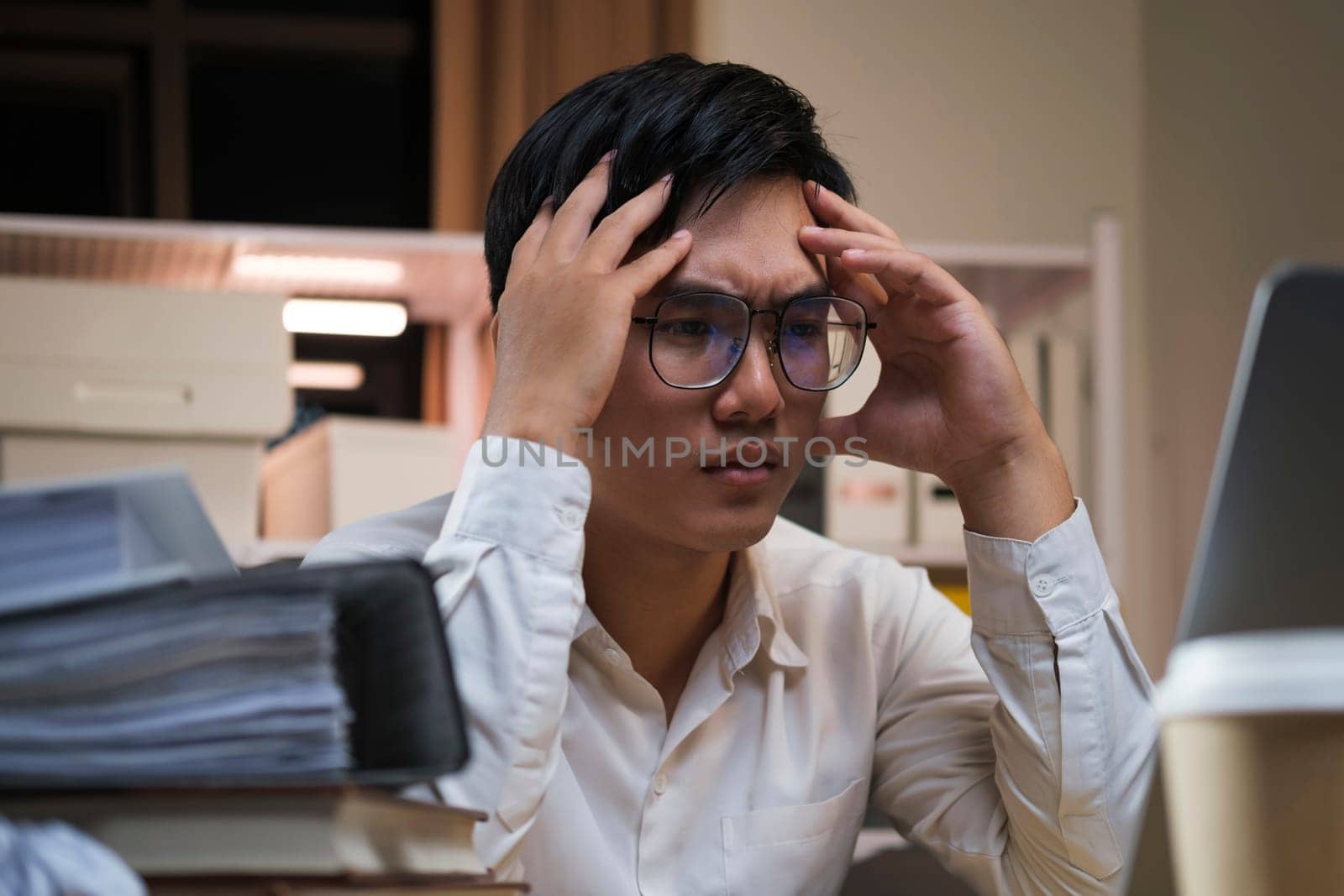Asian young tired staff businessman using desktop computer having overwork project overnight in office.