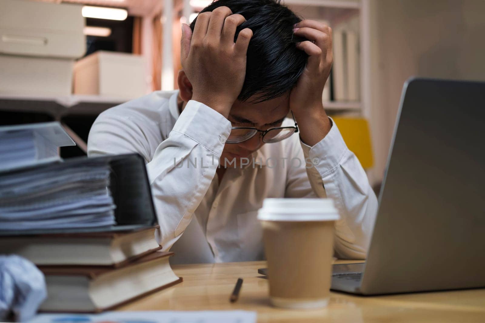 Asian young tired staff businessman using desktop computer having overwork project overnight in office. by ijeab