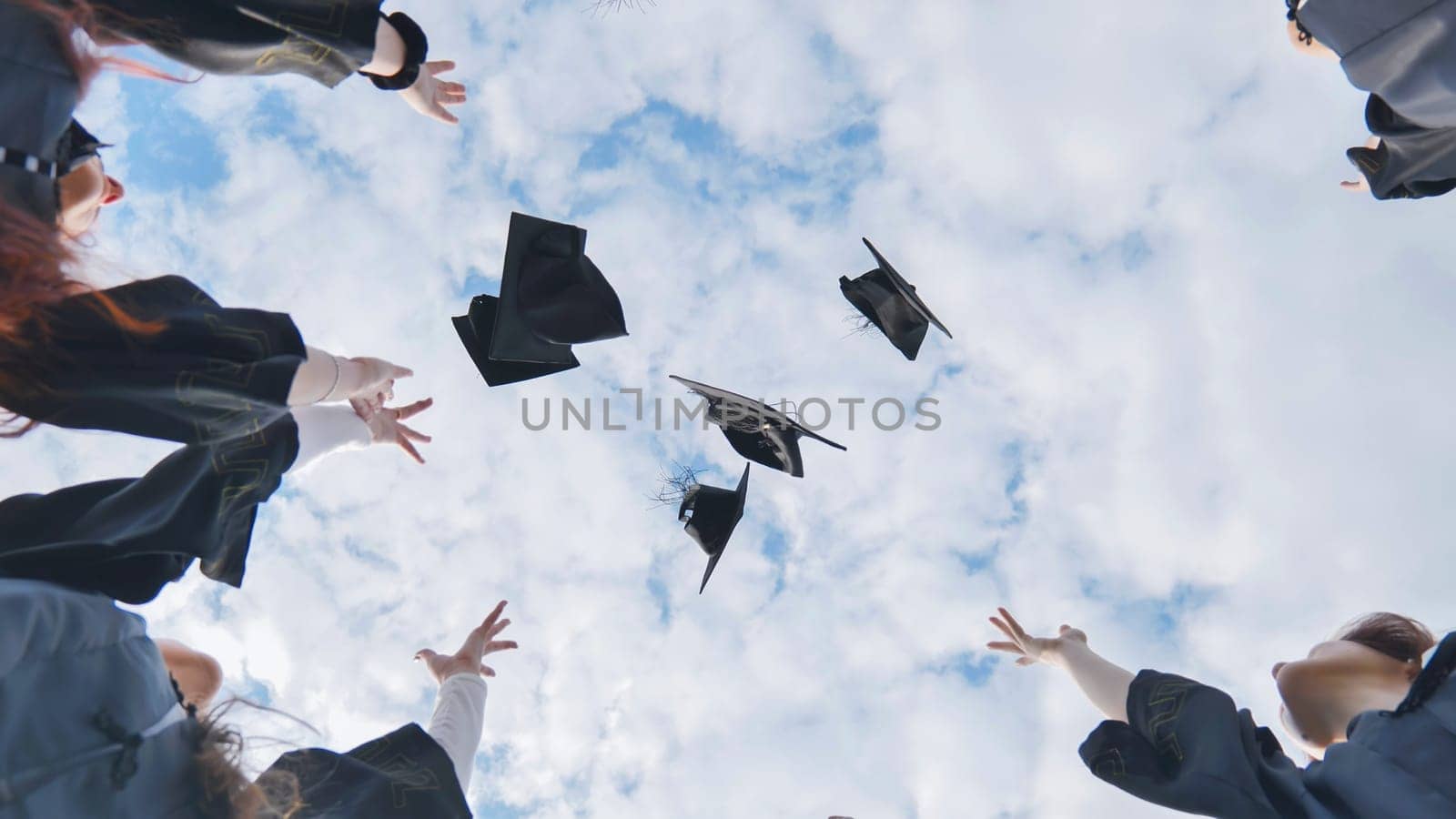 Silhouettes of Happy college graduates tossing their caps up at sunset.