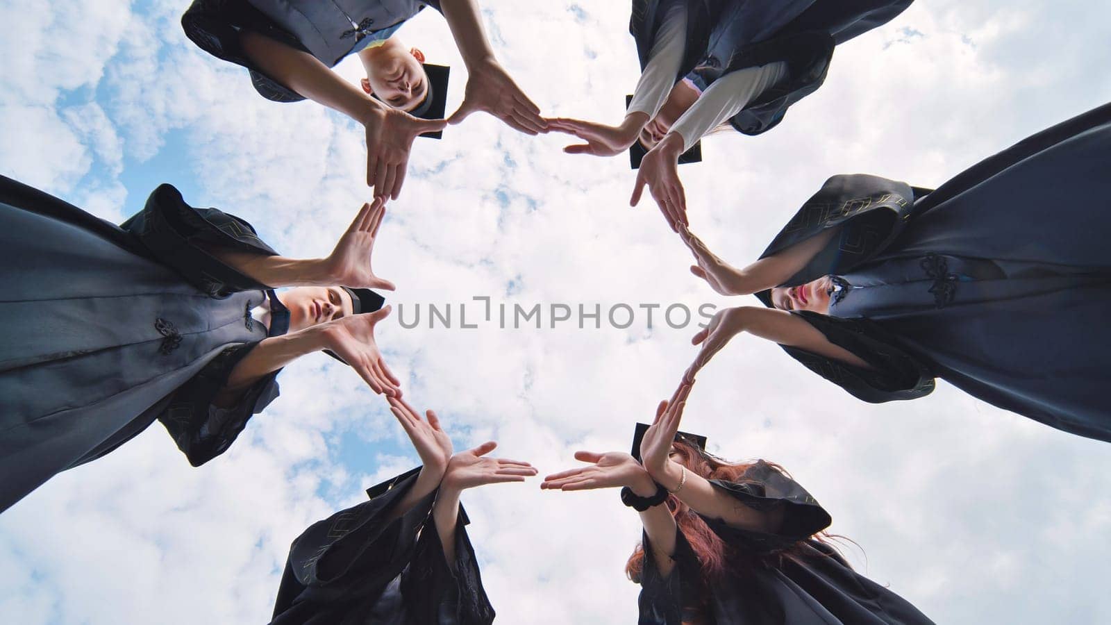 College graduates make a circle of their hands. by DovidPro