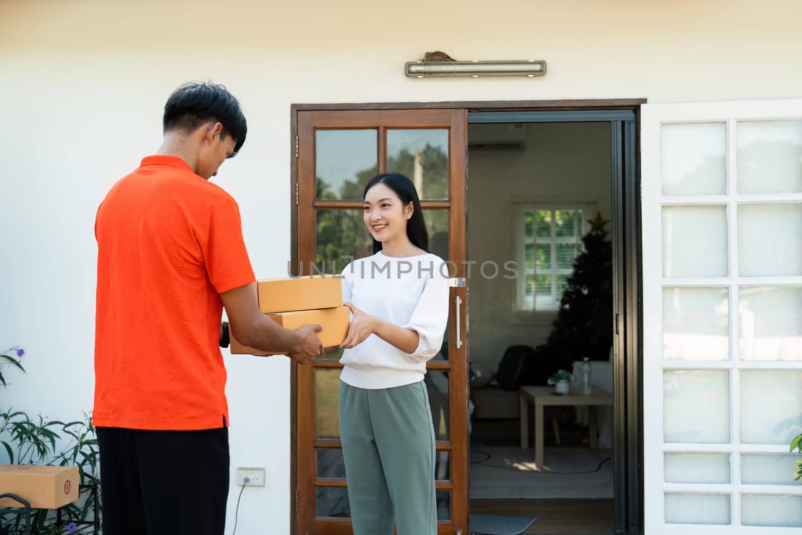 Young Asian cute girl receiving boxes from postman at the door. Delivery concept.