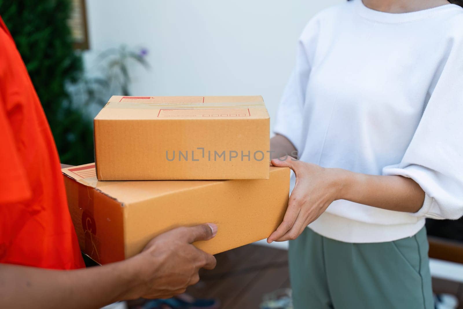 Young Asian cute girl receiving boxes from postman at the door. Delivery concept.