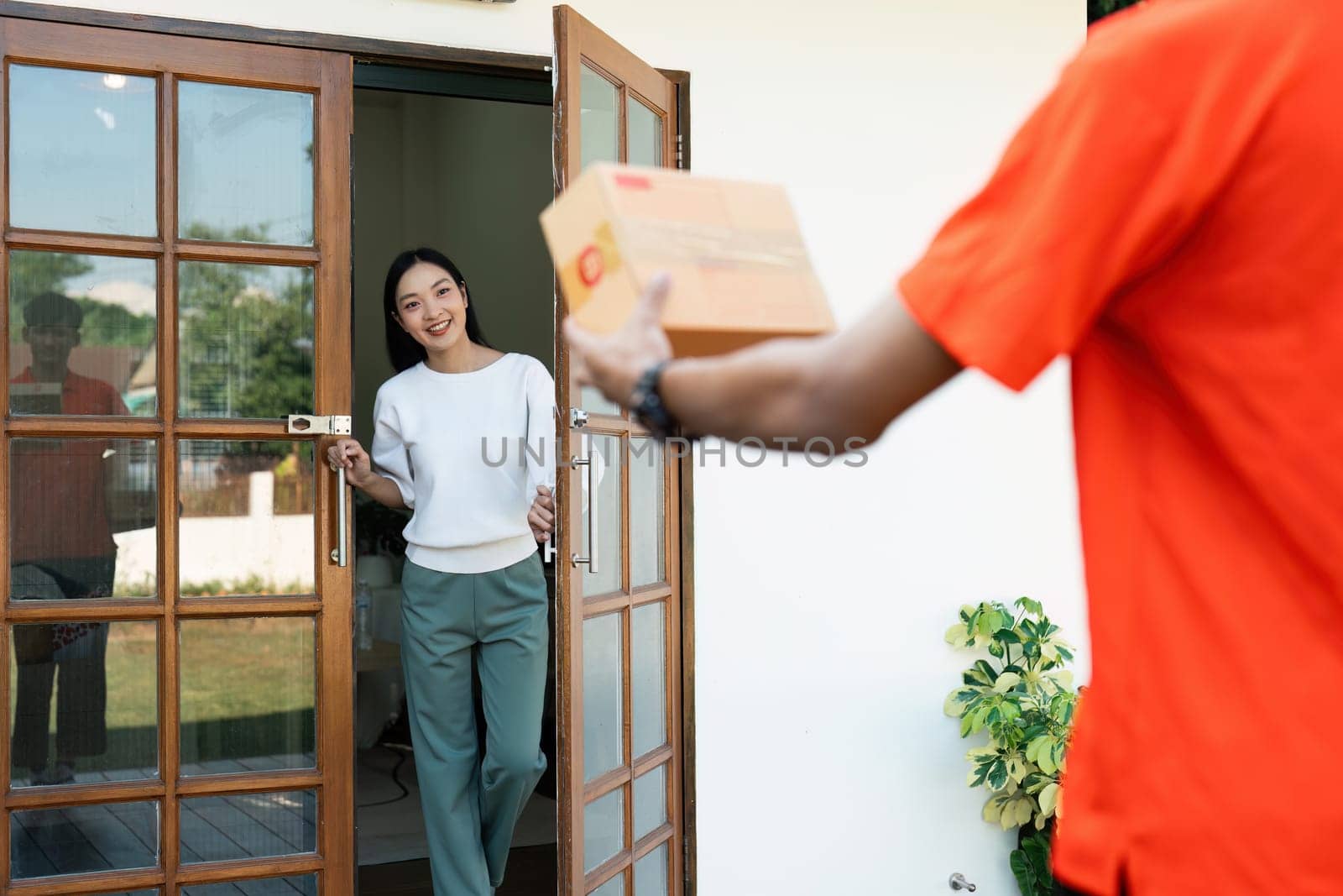 Young Asian cute girl receiving boxes from postman at the door. Delivery concept.