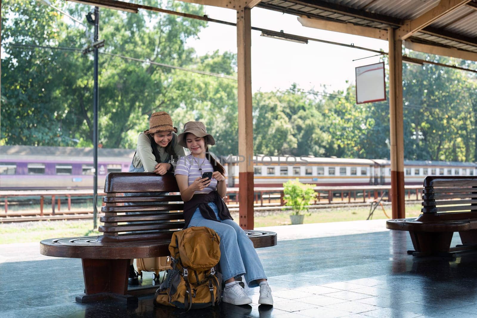 Asian woman friends at railway station have happy moment. Tourism and travel by itchaznong