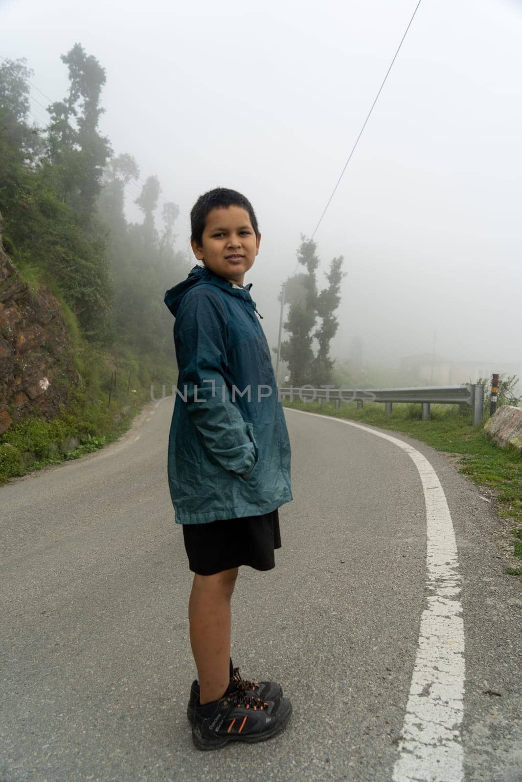 In the picturesque landscapes of Uttarakhand, a young boy stands by the roadside, his journey unfolding against the backdrop of scenic beauty.