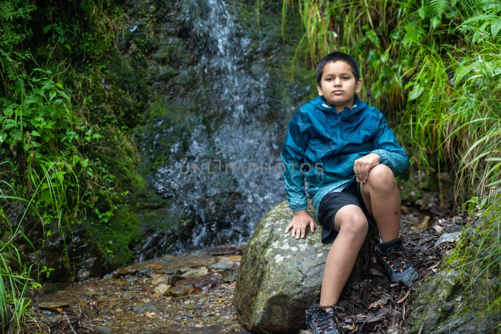 In the heart of nature, an Indian boy seated on a timeless stone.