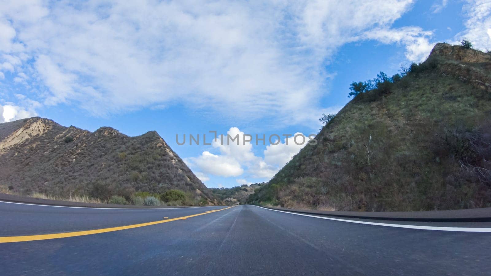 Vehicle is cruising along the Cuyama Highway under the bright sun. The surrounding landscape is illuminated by the radiant sunshine, creating a picturesque and inviting scene as the car travels through this captivating area.