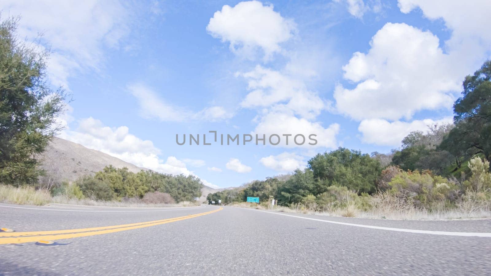 Vehicle is cruising along the Cuyama Highway under the bright sun. The surrounding landscape is illuminated by the radiant sunshine, creating a picturesque and inviting scene as the car travels through this captivating area.