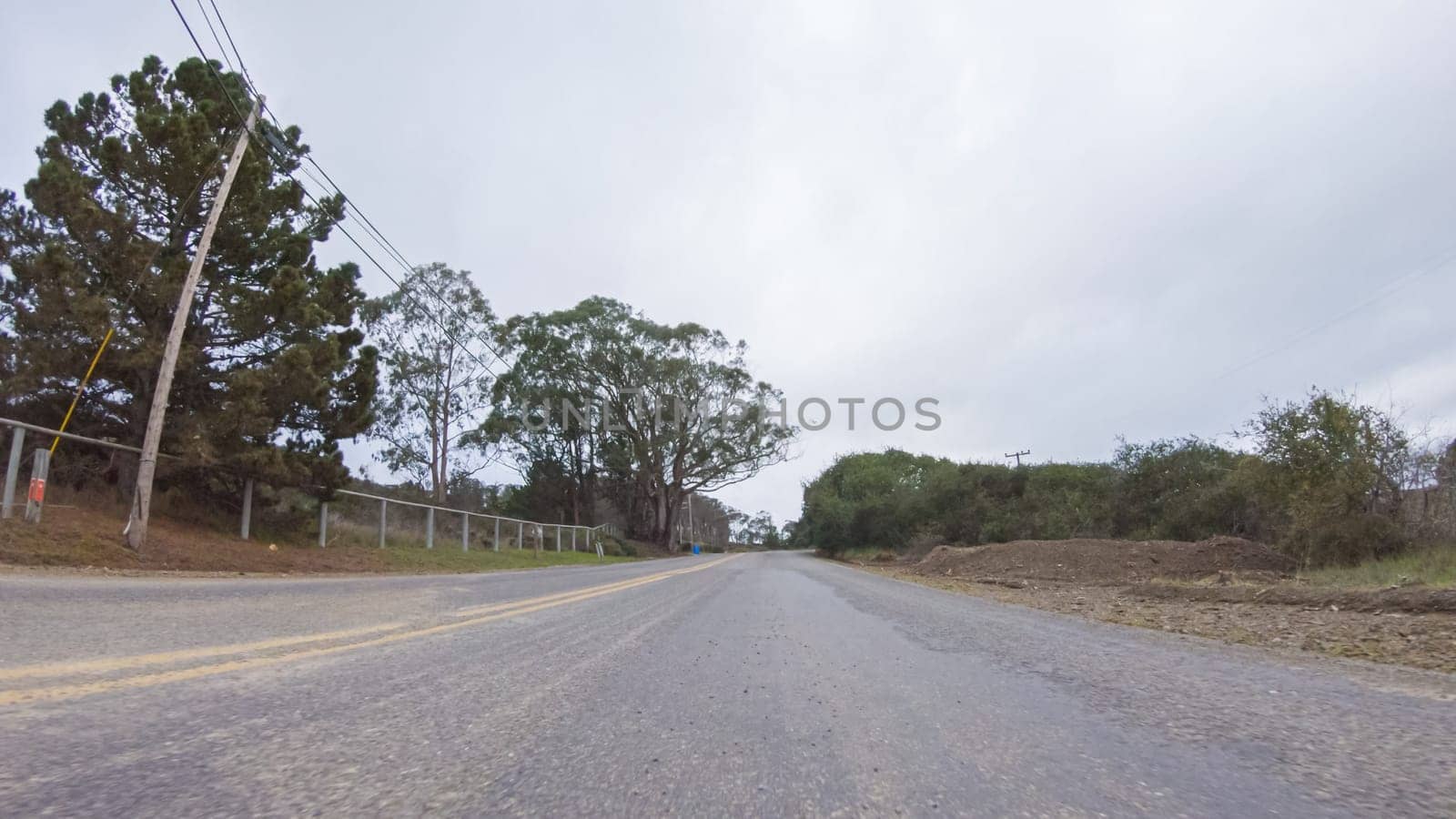 Vehicle navigates the streets of Morro Bay, California, during a cloudy winter day. The atmosphere is moody and serene as the overcast sky casts a soft light on the charming buildings and quiet streets of this coastal town.