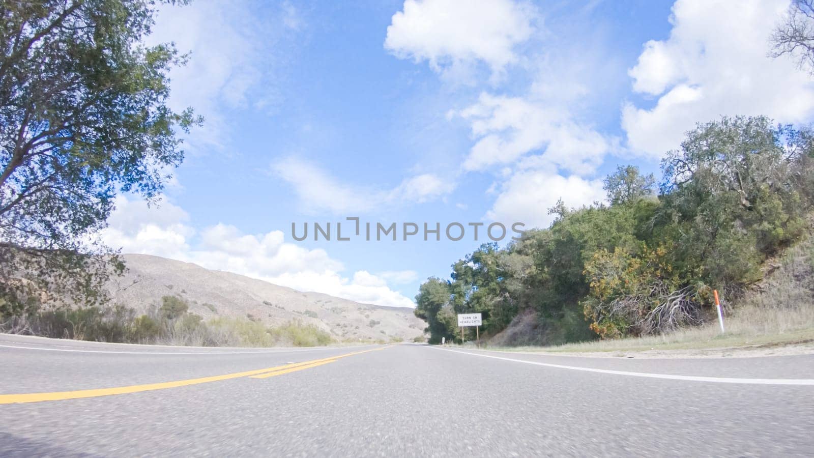 Vehicle is cruising along the Cuyama Highway under the bright sun. The surrounding landscape is illuminated by the radiant sunshine, creating a picturesque and inviting scene as the car travels through this captivating area.