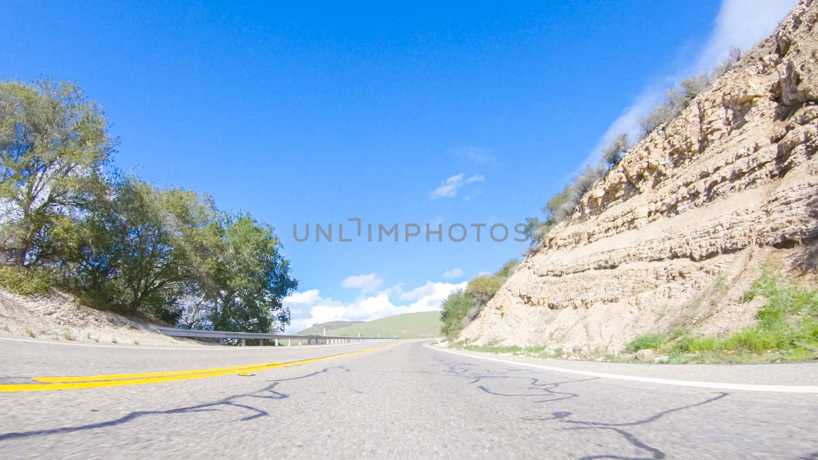 Vehicle is cruising along the Cuyama Highway under the bright sun. The surrounding landscape is illuminated by the radiant sunshine, creating a picturesque and inviting scene as the car travels through this captivating area.