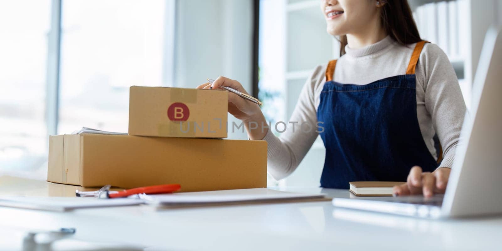 Young business woman entrepreneur online shipment business is preparing packages to send to customer. e-commerce concept.