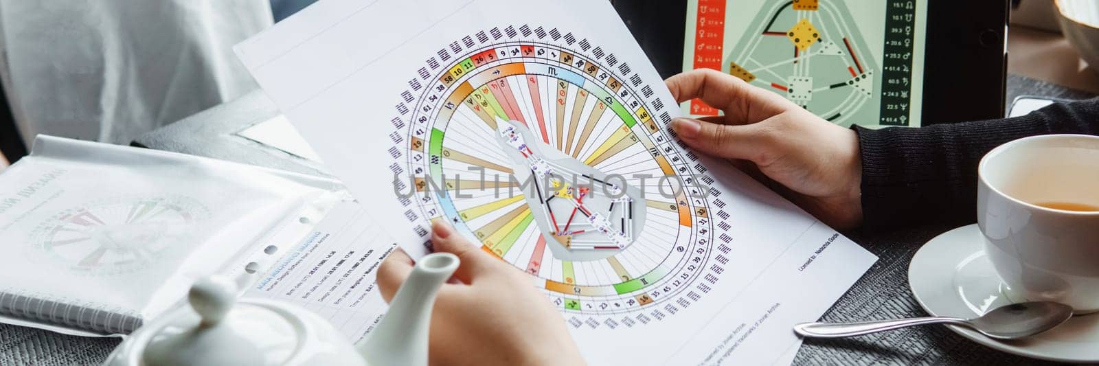 TVER, RUSSIA - FEBRUARY 12, 2023: A woman at the table is studying a rave mandala by human design. Rave mandala on the table close-up. The concept of esoteric teachings