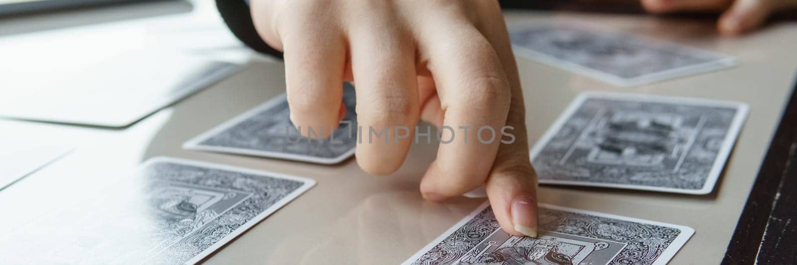 TVER, RUSSIA - FEBRUARY 11, 2023. Tarot cards, Tarot card divination, esoteric background. A woman makes a layout on the cards at the table. Divination, predictions on tarot cards
