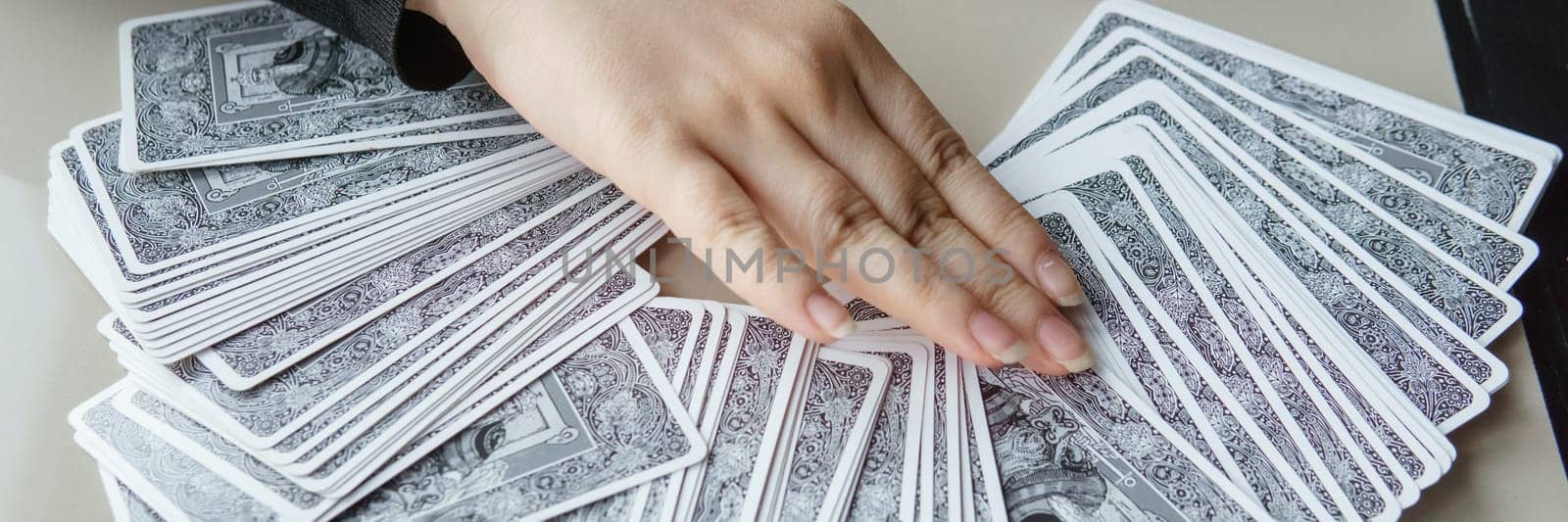 TVER, RUSSIA - FEBRUARY 11, 2023. Tarot cards, Tarot card divination, esoteric background. A woman makes a layout on the cards at the table. Divination, predictions on tarot cards