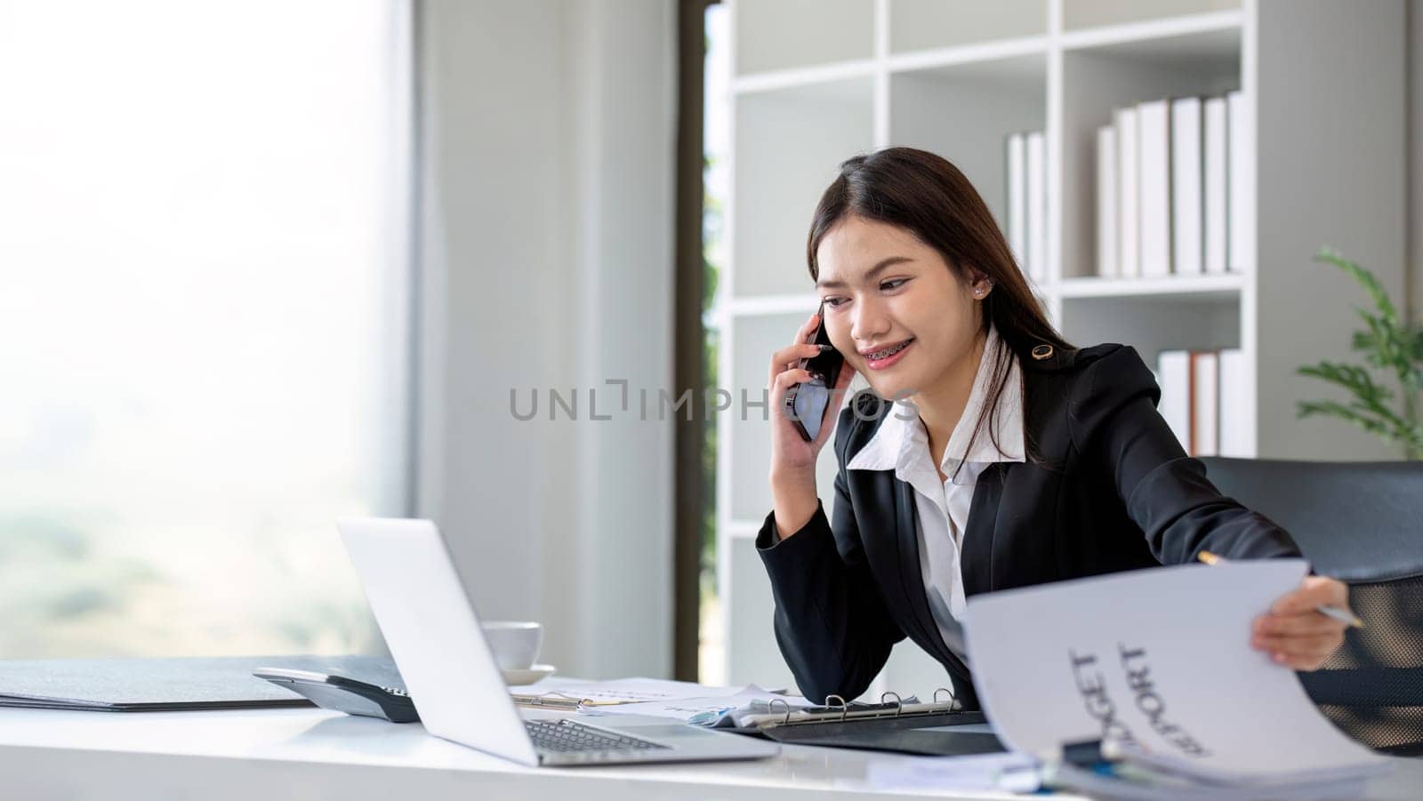 Happy asian business woman have the joy of talking on the smartphone, tablet and laptop on the modern office by wichayada